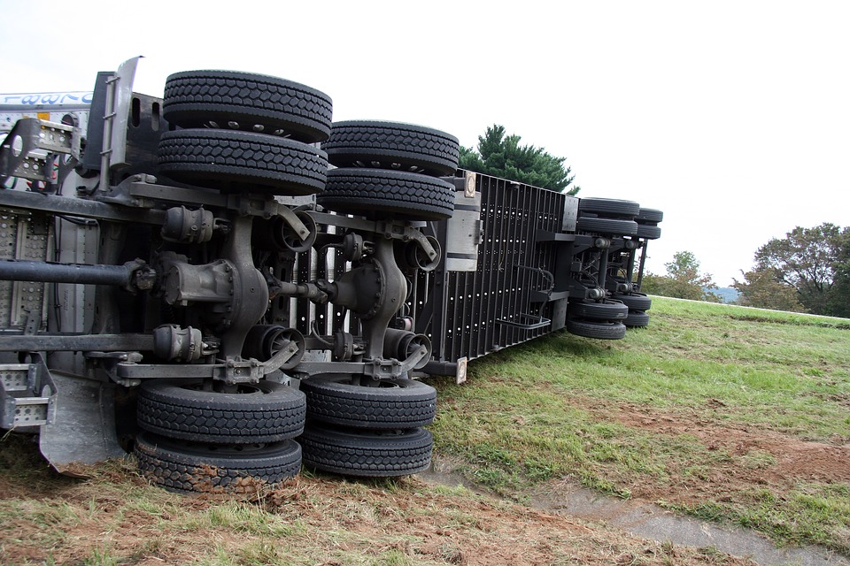 18-wheeler truck resting on its side in the grass