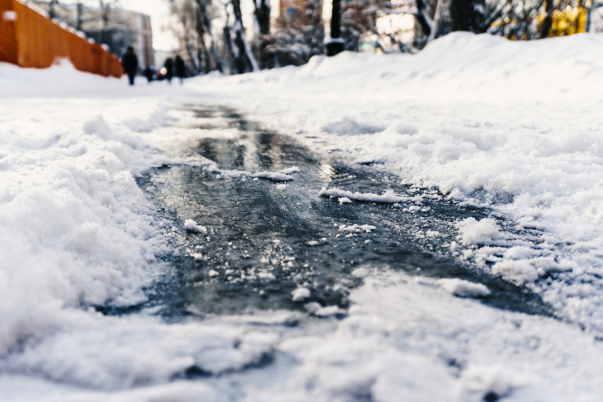 close view of a sidewalk that hasn't been well cleared of snow, appearing icy and shiny, primed for a slip and fall accident