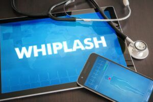 tablet with image of the word whiplash next to phone and stethoscope