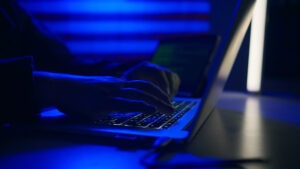 Hacker with laptop and USA flag in background. Cyber attack concept