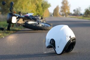 A motorcycle and a helmet are on the ground, after a motorcycle crash.