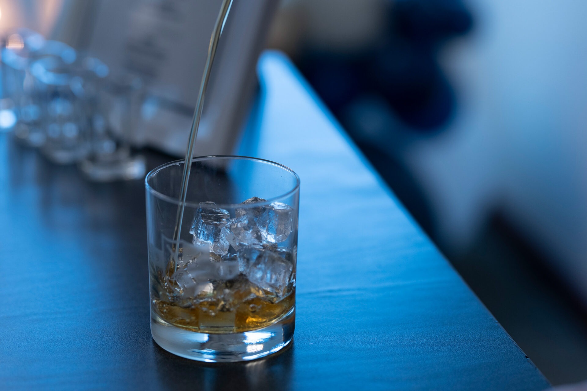 a bartender pouring hard alcohol into a glass with ice at a private event