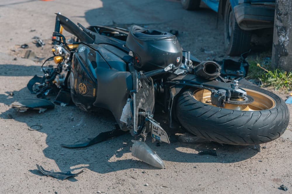 Damaged motorcycle lying on the road after a severe collision, showing the aftermath of a traffic accident.